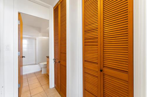 a bathroom with a toilet and a wooden closet at Ilikai Marina 1BR Condo, Ocean View Haven in Honolulu