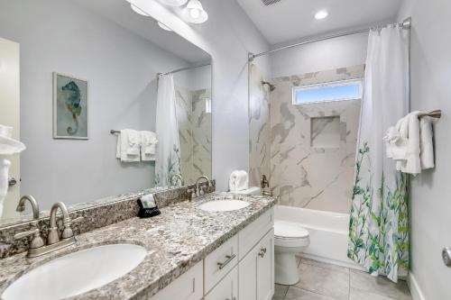 een badkamer met 2 wastafels, een douche en een toilet bij Seaward Breeze in Galveston