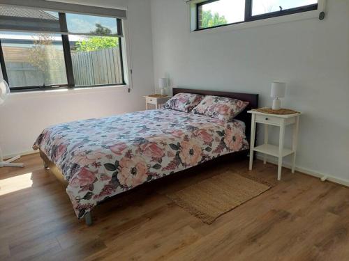 a bedroom with a bed with a floral bedspread and two windows at Lake and Railway Guesthouse in Drysdale