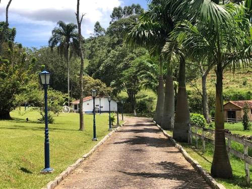 a dirt road with palm trees and a building at Pousada Solar Azul in Miguel Pereira