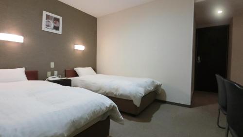 Habitación de hotel con 2 camas con sábanas blancas en Honjo Grand Hotel Vacation STAY 35750, en Yurihonjo