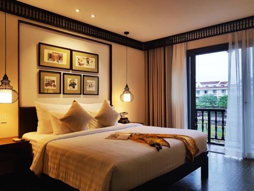 - une chambre avec un grand lit et une fenêtre dans l'établissement Little Hoi An . A Boutique Hotel & Spa, à Hội An