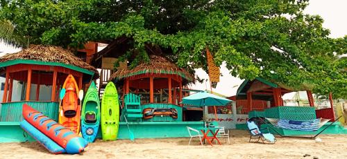- un bâtiment avec des planches de surf sur la plage, une table et des chaises dans l'établissement SmallFry's Beach Resort, à Calatrava