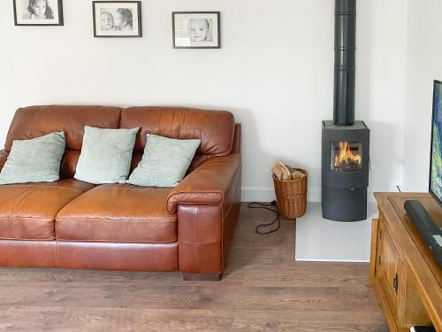 a leather couch in a living room with a wood stove at The Cabin in Southbourne