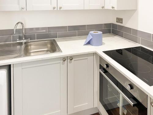 a kitchen with white cabinets and a sink at The Cabin in Southbourne