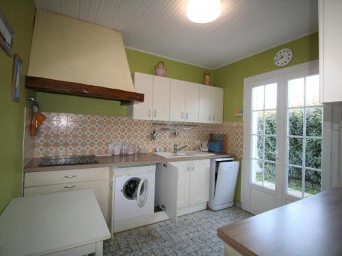 une cuisine aux murs verts et un lave-linge/sèche-linge. dans l'établissement Maison Plain-Pied Centre-Ville, Proche Plage, Jardin Privé, Parking, Animaux Acceptés - FR-1-22-251, à La Tranche-sur-Mer