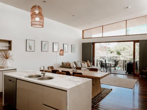 a kitchen and living room with a couch and a table at Byron Butter Factory Apartments in Byron Bay