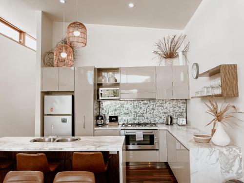 a kitchen with white cabinets and a marble counter top at Byron Butter Factory Apartments in Byron Bay