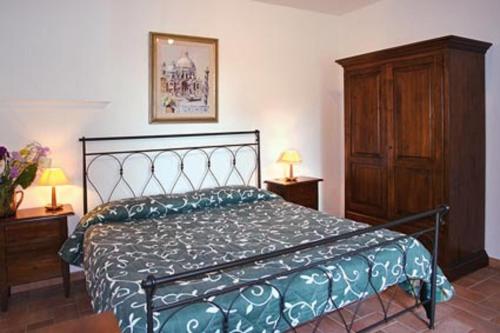 サン・ジミニャーノにあるAppartamento La Palmaのベッドルーム1室(ベッド1台付)、木製キャビネットが備わります。