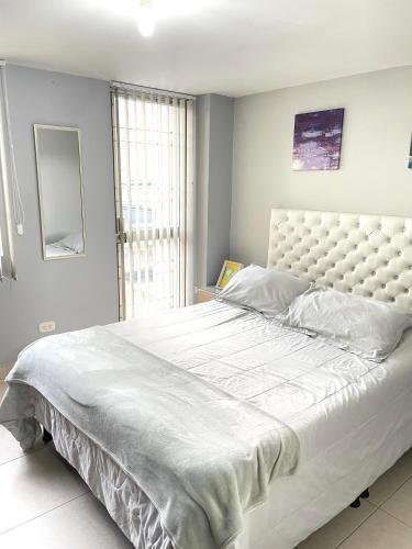 1 dormitorio con 1 cama blanca grande y ventana grande en Hermoso apartaestudio moderno valle de atriz norte, en Pasto