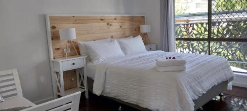 1 dormitorio con cama blanca y ventana en Maple Villa - The Beach House by the bay en Brisbane