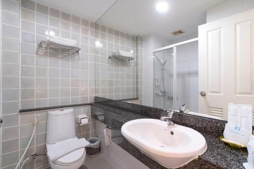 a bathroom with a sink and a toilet and a mirror at Bangkok Loft Inn in Bangkok