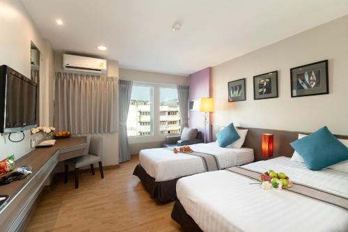 a hotel room with two beds and a television at Bangkok Loft Inn in Bangkok