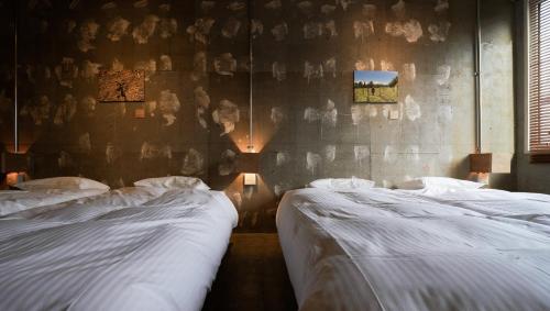 two beds in a room with a wall at Yoichi LOOP in Kurokawamachi