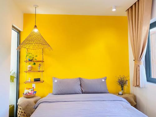 a yellow bedroom with a bed and a yellow wall at Nhà Sói Homestay Da Lat in Da Lat