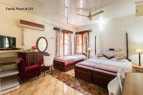 1 dormitorio con 2 camas, escritorio y espejo en Sonnetta Residency, en Kochi