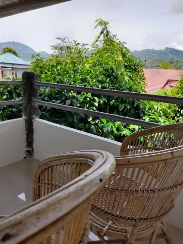 Duas cadeiras de vime sentadas em cima de uma varanda em Hotel Pison em Rantepao