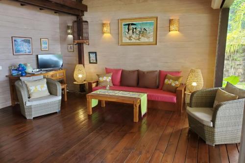 a living room with a red couch and two chairs at Cottage Miti Reva in Haapiti