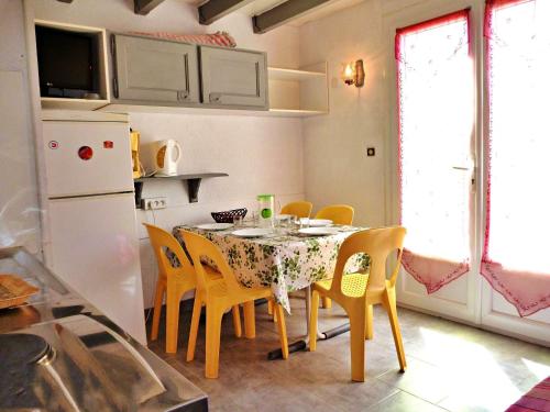 une cuisine avec une table avec des chaises et un réfrigérateur dans l'établissement Charmante Maisonnette avec Piscine près de la Plage, Parking, et Animaux Acceptés - FR-1-387-103, à Marseillan