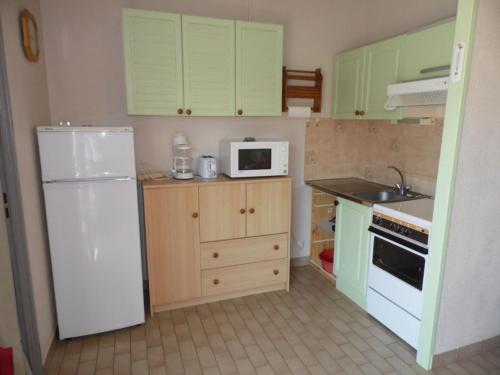 Elle comprend une petite cuisine avec des placards verts et un réfrigérateur blanc. dans l'établissement Studio cab. climatisé avec terrasse, pk privé et piscine - Grau d'Agde - FR-1-423-35, au Grau-dʼAgde