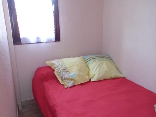 une chambre avec un lit avec deux oreillers dessus dans l'établissement Studio cab. climatisé avec terrasse, pk privé et piscine - Grau d'Agde - FR-1-423-35, au Grau-dʼAgde