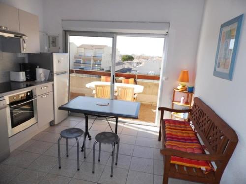 une cuisine avec une table et des chaises et une cuisine avec un balcon dans l'établissement Appartement 2 pièces avec mezzanine, terrasse et piscine à Marseillan-Plage - FR-1-326-528, à Marseillan