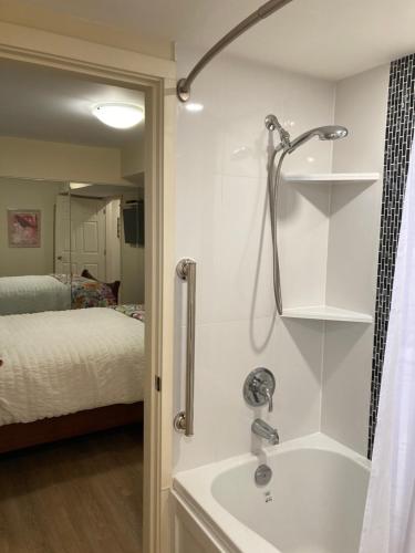 a bathroom with a shower and a sink and a bed at Bright poolside walkout two bedroom basement suite in the Okanagan in Penticton