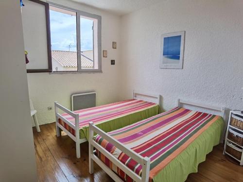 une chambre avec deux lits et une fenêtre dans l'établissement Appartement 3 pièces, 6 couchages avec terrasse et parking privé, proche de la plage à Marseillan - FR-1-326-697, à Marseillan