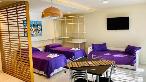 Habitación con camas de color púrpura, mesa y TV. en ALQUILER TEMPORARIO UNIVERSAL en Godoy Cruz