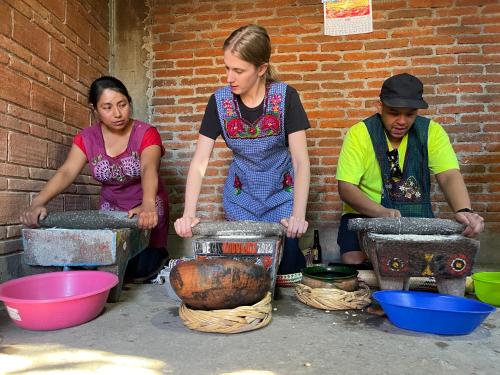 three women are preparing food in pots on a street at LÍZU Tu casa en un pueblo zapoteca in Teotitlán del Valle