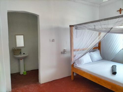 um quarto com uma cama e um lavatório num quarto em Mambo Leo Hostel em Paje