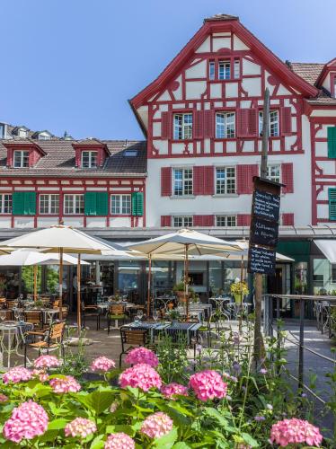 a building with tables and chairs and pink flowers at Hotel Hofgarten Luzern in Luzern