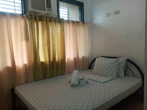 Schlafzimmer mit einem Bett und einem Fenster mit Vorhängen in der Unterkunft Alabang Condotel in Manila
