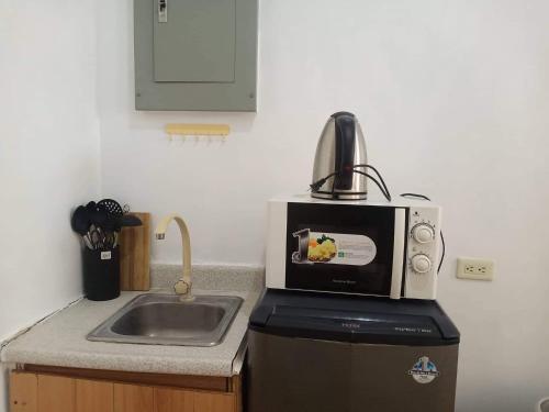 eine Küche mit einer Spüle und einer Mikrowelle in der Unterkunft Alabang Condotel in Manila