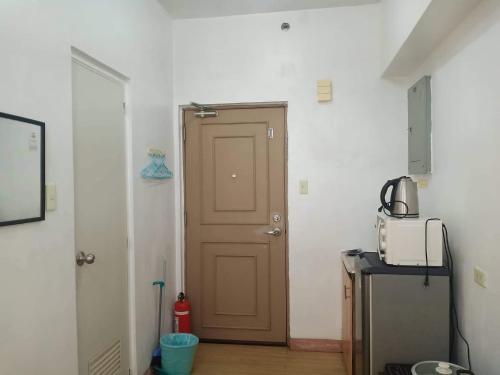 eine Tür in einem Zimmer mit einer Mikrowelle und einem Kühlschrank in der Unterkunft Alabang Condotel in Manila