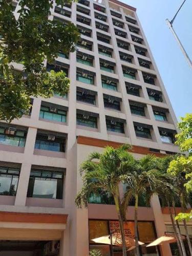 a tall building with palm trees in front of it at Alabang Condotel in Manila