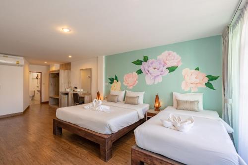 two beds in a room with flowers painted on the wall at B House Chiang Mai Thailand in Chiang Mai