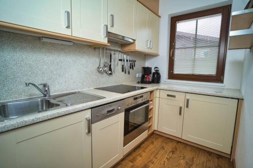 a kitchen with white cabinets and a sink and a window at Ferienhof Stöckl in Finkenberg