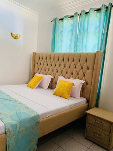 a bed with two pillows on it in a room at Lux Suites Mahesh Doshi Apartments Nyali in Mombasa