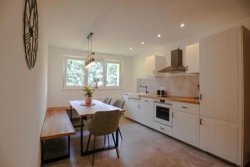 een keuken met witte kasten en een tafel. bij Ferienwohnung Holiswald in Oppenau