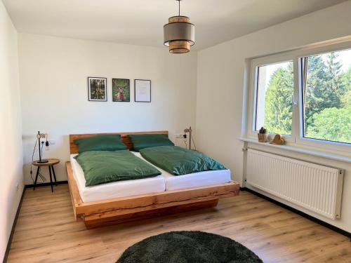 een slaapkamer met een bed met groene lakens en een raam bij Ferienwohnung Holiswald in Oppenau