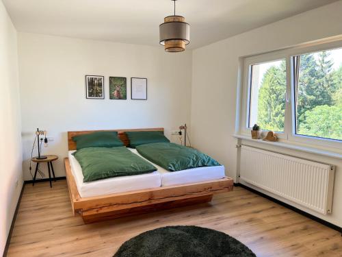 a bedroom with a bed with green sheets and a window at Ferienwohnung Holiswald in Oppenau
