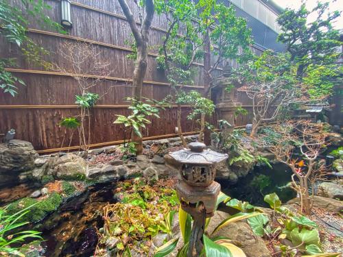 a garden with a stone fountain in front of a fence at Ryokan Sawaya Honten in Kyoto