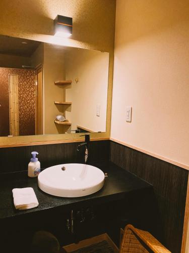 a bathroom with a sink and a large mirror at Ryokan Sawaya Honten in Kyoto