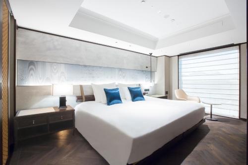 a bedroom with a large white bed with blue pillows at Dhawa Yura Kyoto in Kyoto