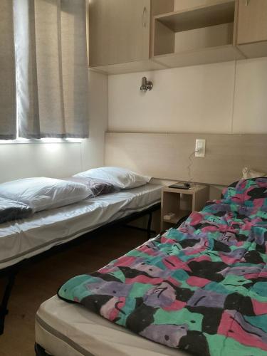 deux lits assis dans une pièce avec un lit carré dans l'établissement Mobilhome « Candice », à Sigean