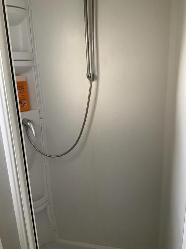une cabine de douche avec un tuyau fixé à un mur dans l'établissement Mobilhome « Candice », à Sigean