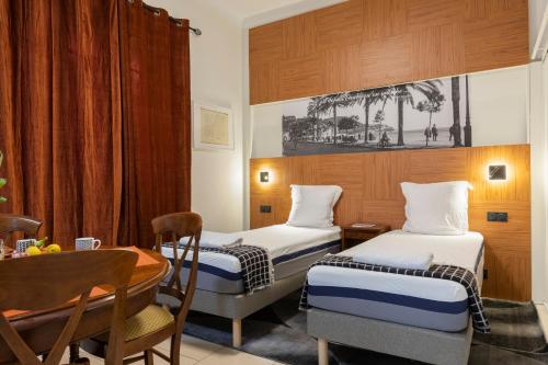 une chambre d'hôtel avec deux lits et une table dans l'établissement La plume de Paul, à Nice