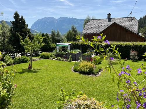 un jardín con un granero y montañas al fondo en Ferienwohnung Sonnschein, en Bad Mitterndorf