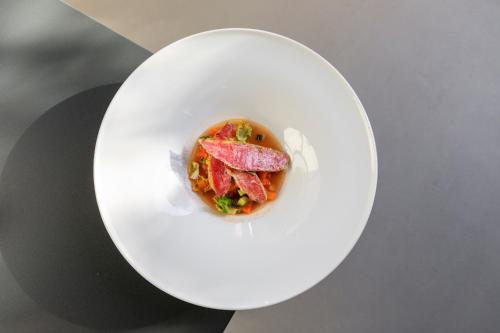 a white plate with a dish of food on a table at Domìa Boutique Hotel e Cucina in Mondello